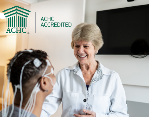 Cedar County Memorial Hospital Sleep Lab is accredited by the Accreditation Commission for Health Care.Photo of a hospital employee preparing a patient for a sleep study by placing electrodes on the patients head. ACHC Accredited logo overlays the image.