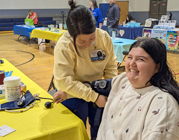 Photo of a nurse putting a cuff on a woman for a blood pressure screening